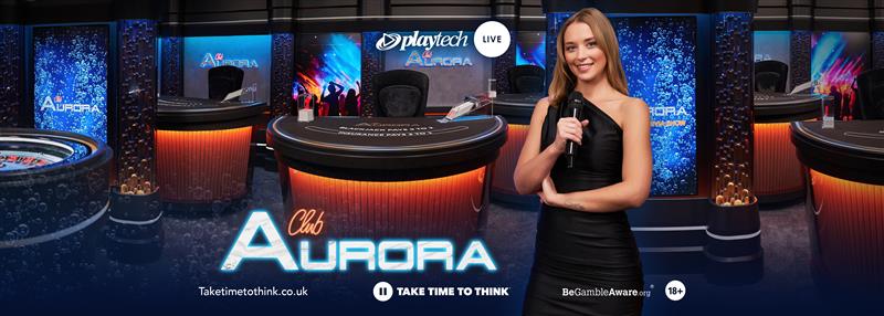 ภาพของโต๊ะคาสิโนใน Club Aurora ที่จัดโดย Playtech พร้อมดีลเลอร์ยิ้มแย้มในเสื้อผ้าสวยงาม พื้นหลังมีสีฟ้าและประดับด้วยแสงไฟสวยงาม